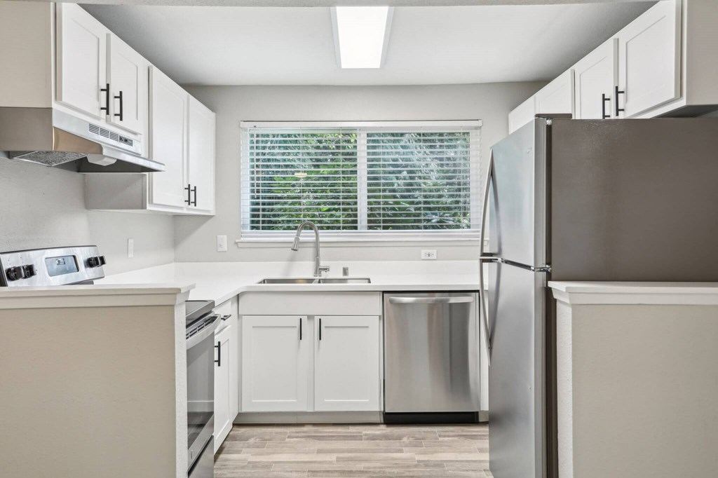 A kitchen with white cabinets and a stainless steel refrigerator.