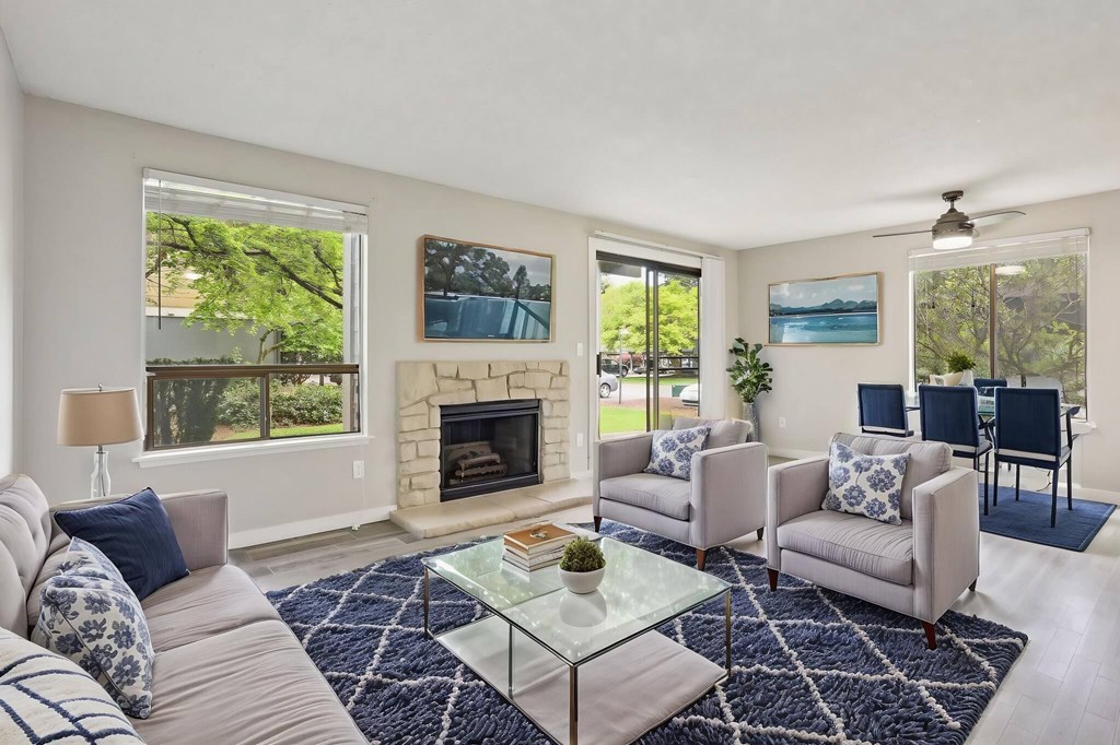 A living room with a fireplace and a glass coffee table.