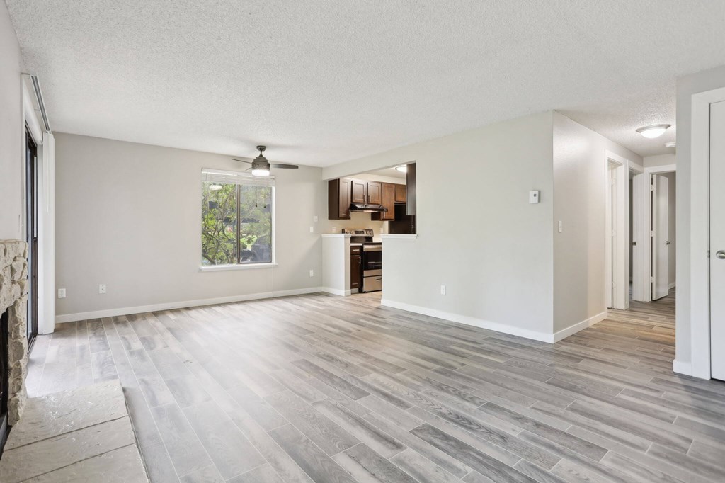 A spacious living room with a fireplace and a ceiling fan.
