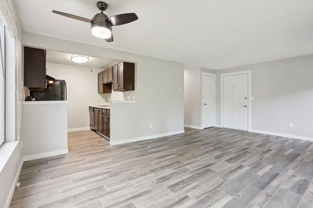 A room with a ceiling fan and wooden flooring.