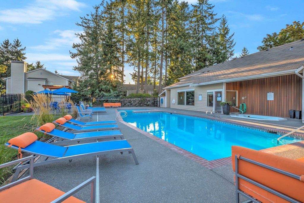 A pool with sun loungers and a building in the background.