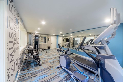 A gym with a row of treadmilers and a row of stationary bikes.