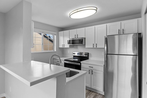A modern kitchen with white cabinets and stainless steel appliances.