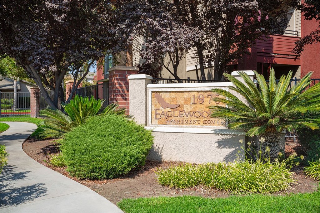 A sign for Eaglewood Apartment Homes is displayed in front of a building.