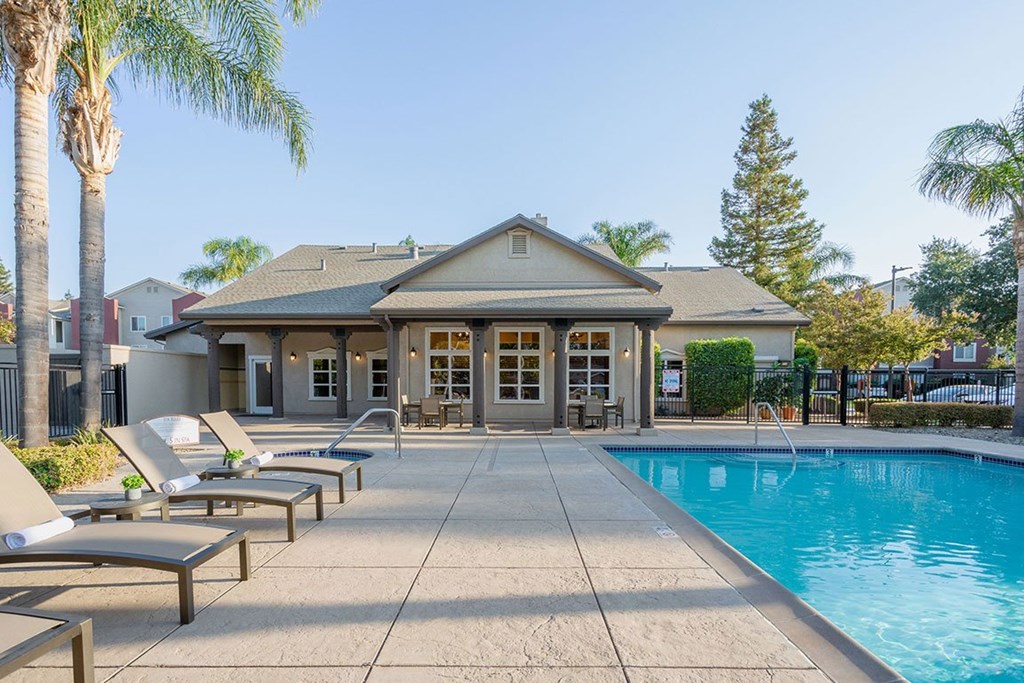 A house with a pool and lounge chairs.