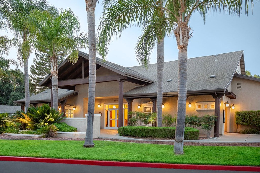 A house with a red curb and palm trees in front.