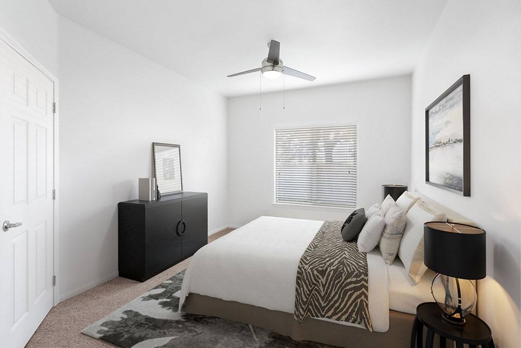 A bedroom with a bed, a dresser, and a ceiling fan.