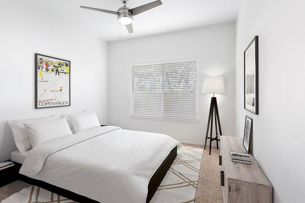 A bedroom with a bed, a ceiling fan, a nightstand, a lamp, a picture frame, and a rug.