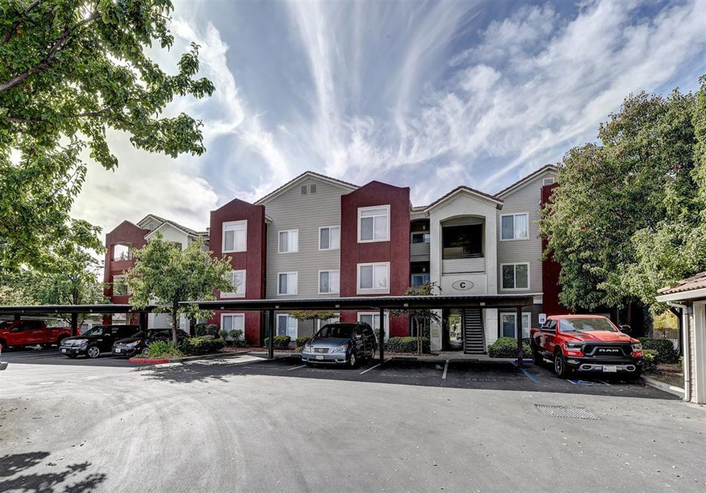 A parking lot in front of a multi-story apartment building.