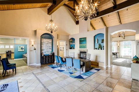 A spacious living room with a large chandelier and a blue and white rug.
