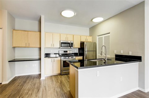 A kitchen with wooden cabinets and black countertops.