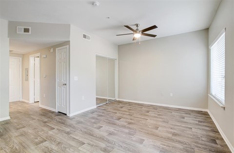 A room with a ceiling fan and light, and a wooden floor.