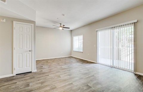 A room with a white door, a ceiling fan, and a window with blinds.