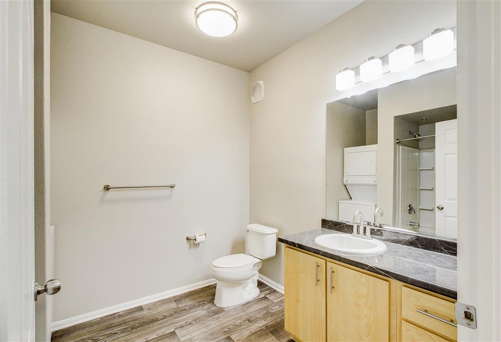 A bathroom with a toilet, sink, and mirror.