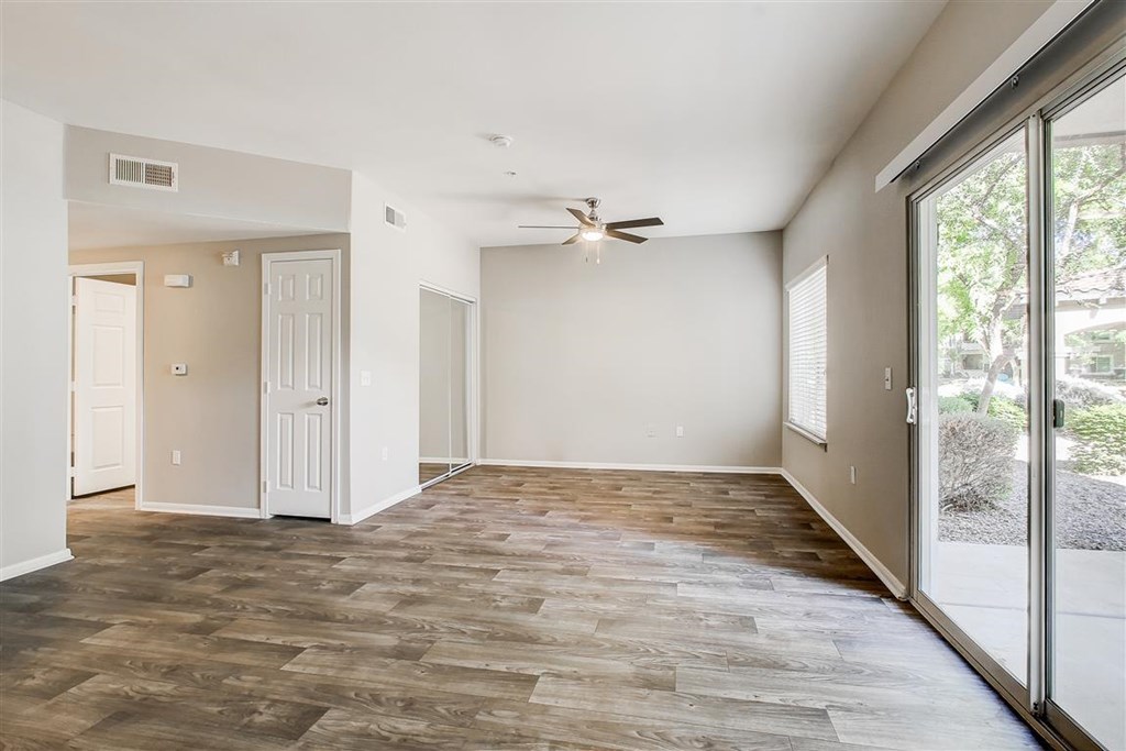 A room with a ceiling fan and sliding glass doors.