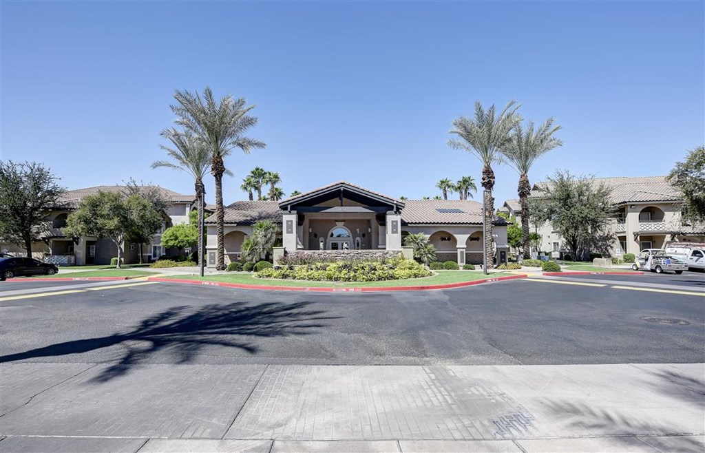 A sunny day at a residential complex with palm trees and a clear blue sky.