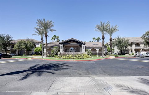 A sunny day at a residential complex with palm trees and a clear blue sky.