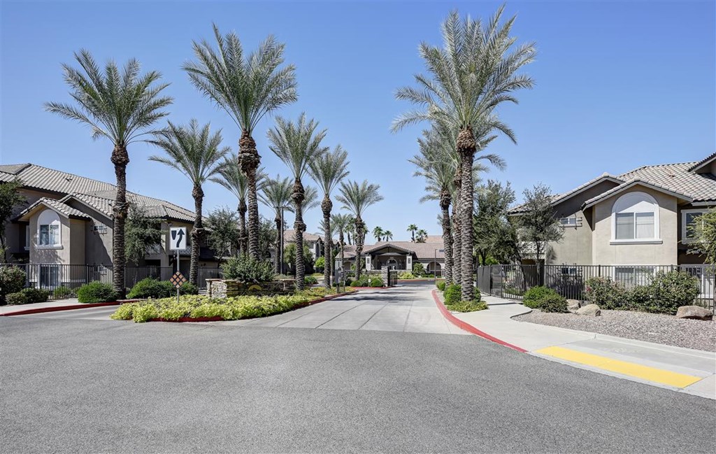 A street with palm trees and houses on both sides.