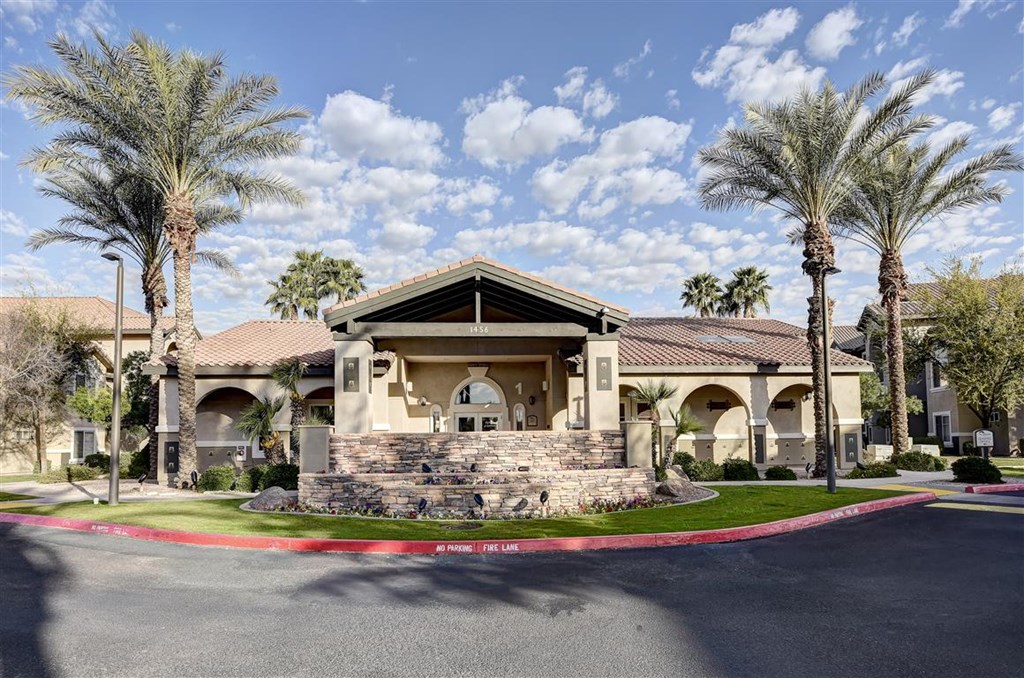 A large house with a stone wall and palm trees in front.
