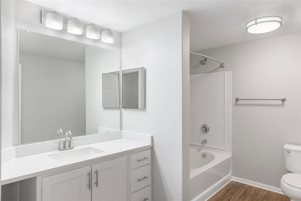 A white bathroom with a sink, mirror, and toilet.
