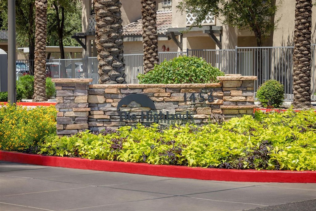 A stone sign with the number 1458 on it is in front of a fence and some trees.