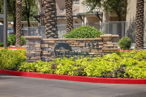 A stone sign with the number 1458 on it is in front of a fence and some trees.