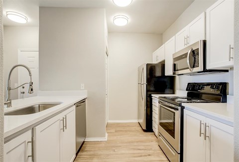 A kitchen with white cabinets and black appliances.