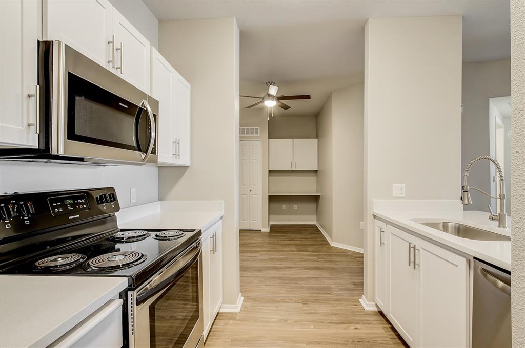 A kitchen with white cabinets and a stove top oven.