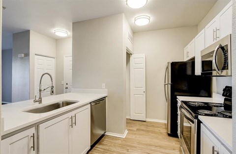 A kitchen with white cabinets and a black refrigerator.