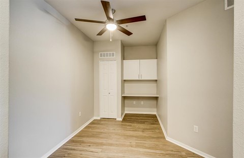 A room with a ceiling fan and a cabinet.
