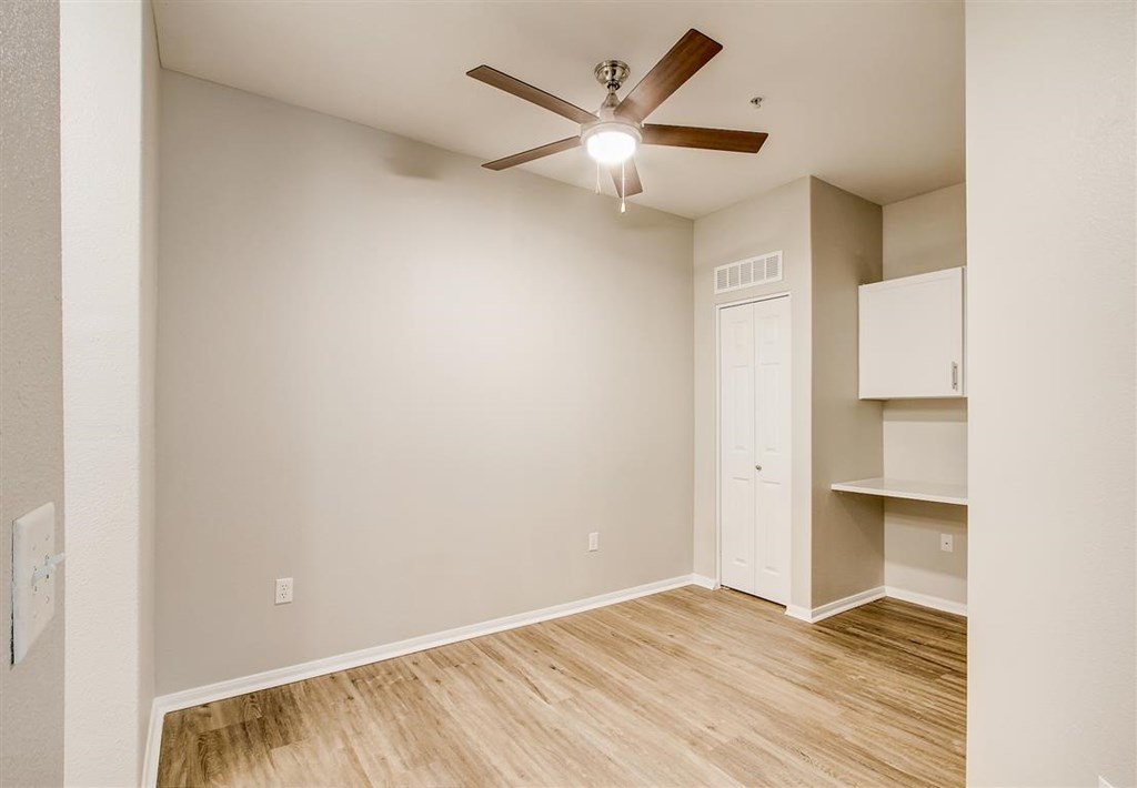 A room with a ceiling fan and a door.