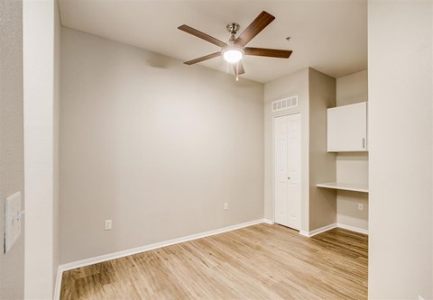 A room with a ceiling fan and a door.