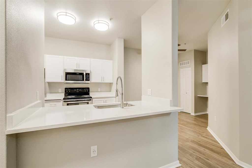 A kitchen with white cabinets and a microwave built into the cabinetry.
