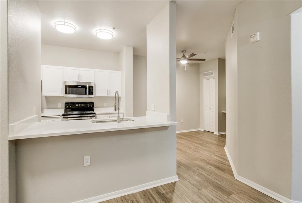A kitchen with white cabinets and a microwave on top of the counter.