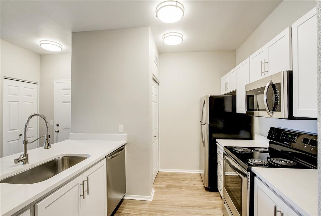 A kitchen with white cabinets and black appliances.