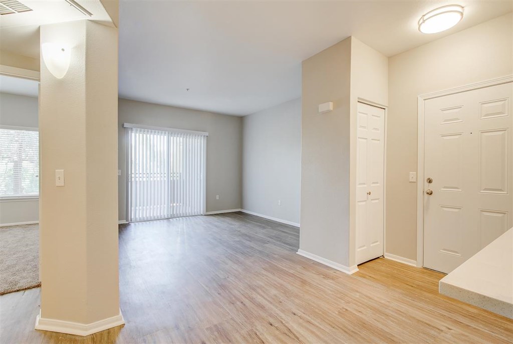 A spacious room with wooden floors and white walls.