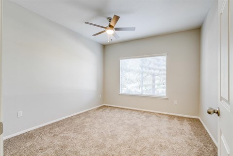 A room with a ceiling fan and carpeted floor.