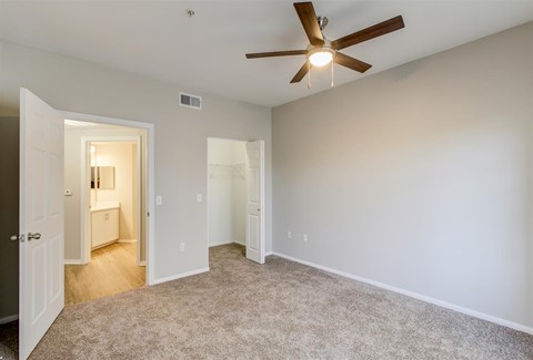 A room with a ceiling fan and carpeted floor.