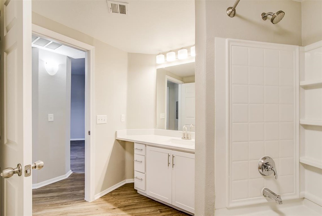 A white bathroom with a walk in shower and a vanity.
