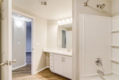 A white bathroom with a walk in shower and a vanity.