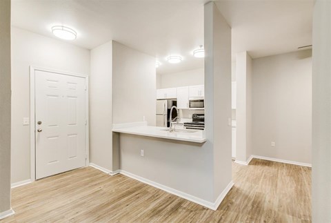 A white door is on the left of a room with a counter and a shelf.