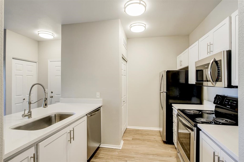 A kitchen with white cabinets and black appliances.