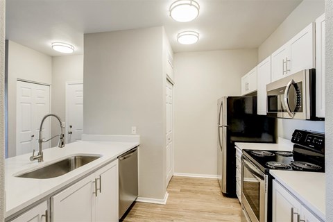 A kitchen with white cabinets and black appliances.