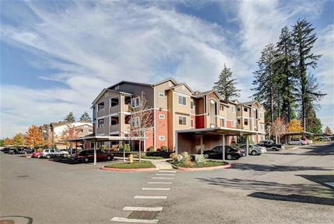 A large apartment complex with a parking lot in front.