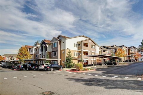 A large apartment complex with a parking lot in front.