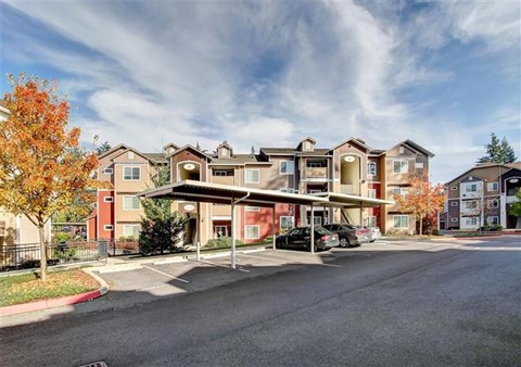 A large apartment complex with a parking lot in front.
