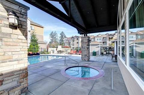 A pool area with a hot tub and a stone pillar.