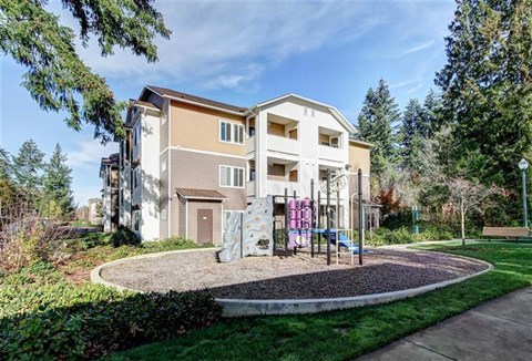 A modern two-story apartment building with a playground in front.