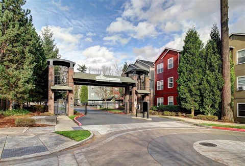 A red building is situated in the middle of a road with a gate in front of it.