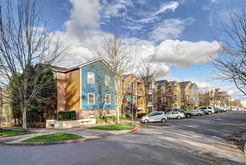 A row of houses with cars parked in front.